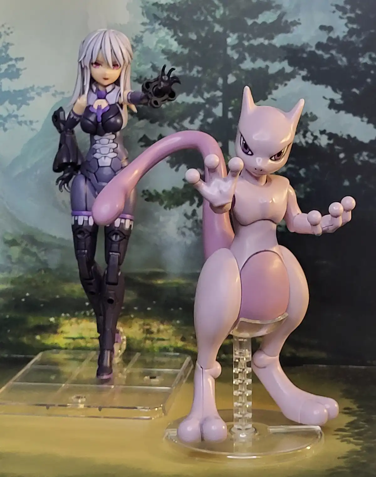 Two anime-style figurines are displayed: a purple-haired female character in a dark outfit holding a weapon, and a pink…