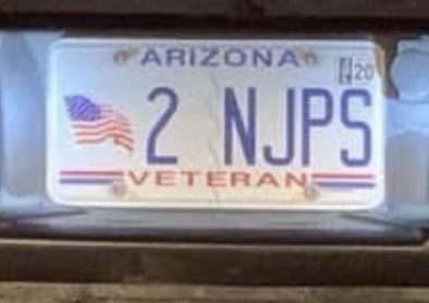 A close-up of an Arizona state license plate that reads '2 NJPS' with 'VETERAN' at the bottom and an American flag on the…