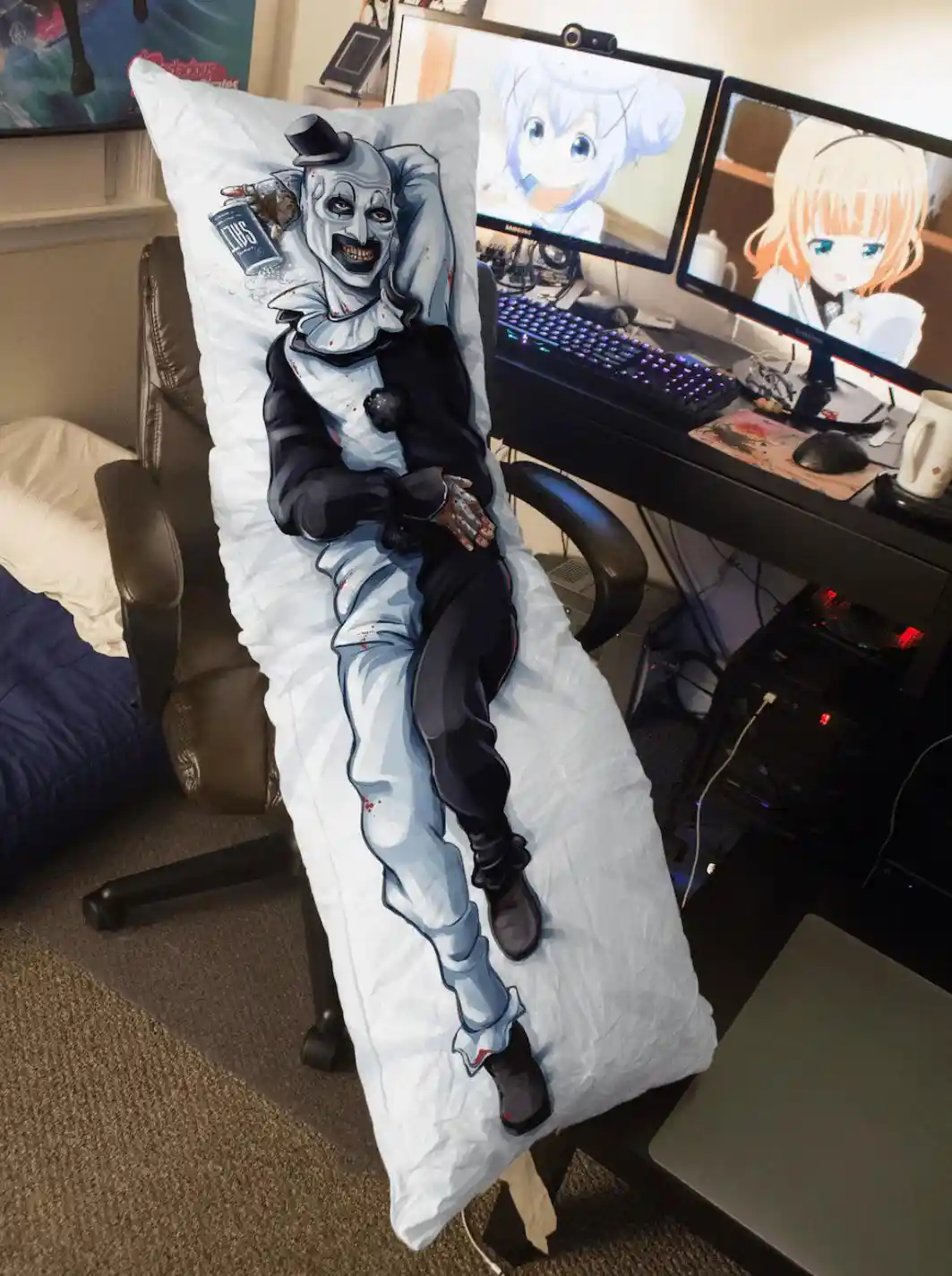 A long body pillow featuring a cartoonish, blood-splattered clown in a top hat and tuxedo, lounging in a gaming chair. The…