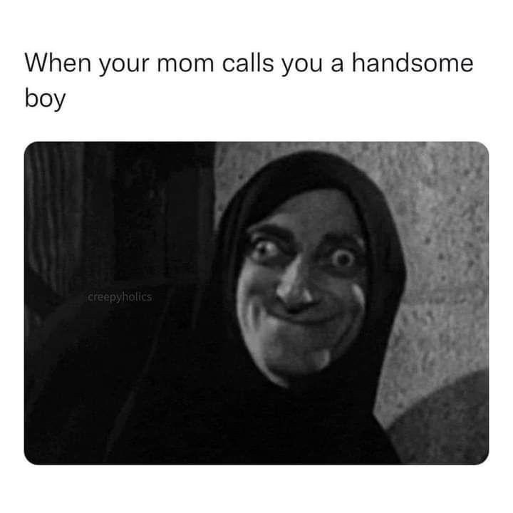 A black-and-white image of a person in a dark hooded garment with an exaggerated, unsettlingly cheerful expression…