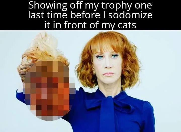 A woman with red hair and a blue bow tie holds up a pixelated object, which appears to be a trophy, while looking directly…