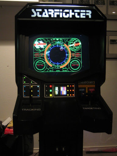 A black arcade cabinet for the game 'Starfighter' displays a glowing green cockpit HUD with targeting reticles and circular…
