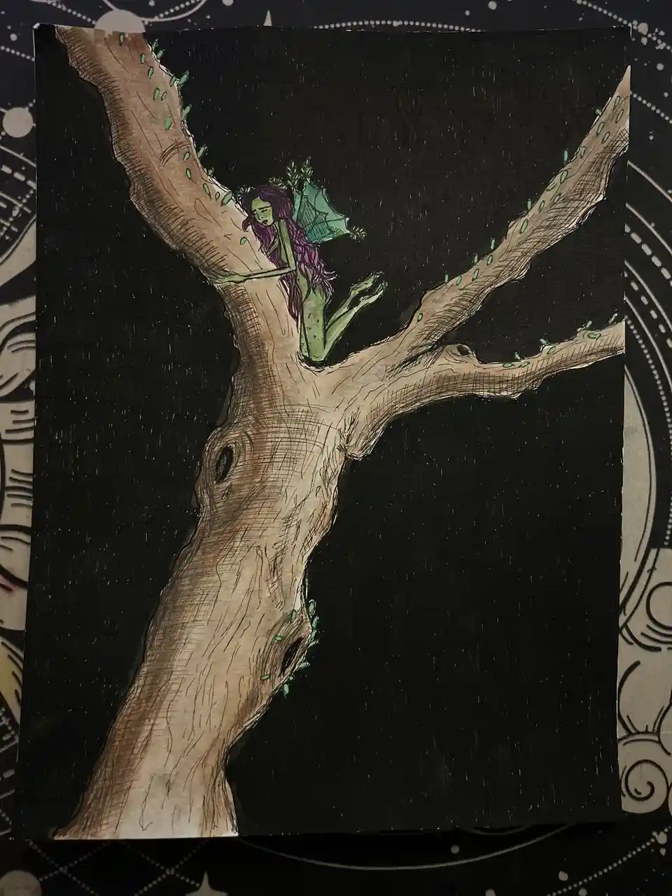 A hand-drawn illustration shows a green-skinned, purple-haired fairy-like creature with wings, perched on a large, gnarled…