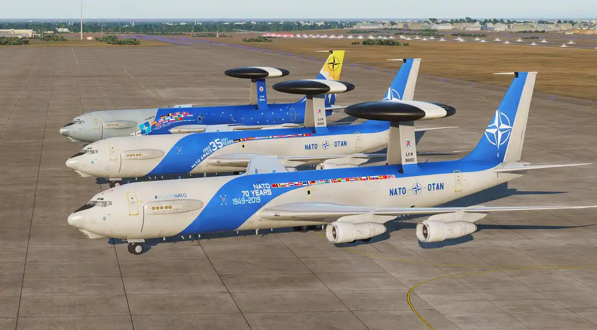 Three NATO E-3 Sentry AWACS aircraft are parked in a row on an airport tarmac, each with distinct commemorative livery…