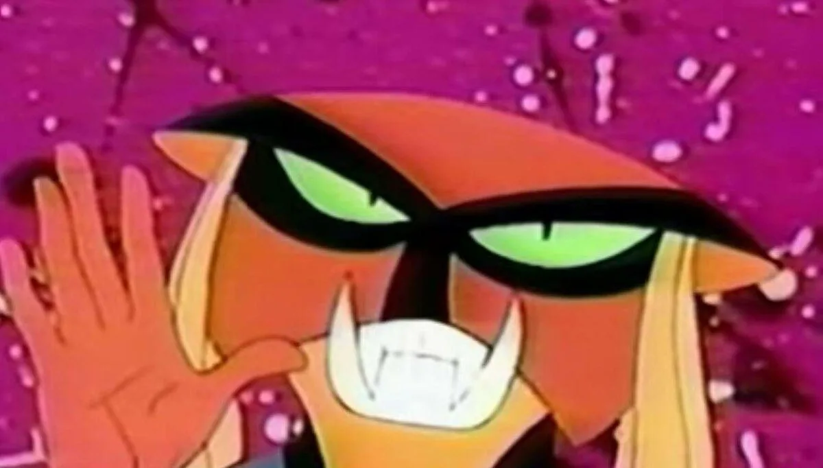 a close-up of the animated character Zim from Invader Zim, who has glowing green eyes, sharp fangs, and is holding up his…