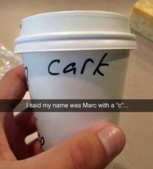 A hand holds a white disposable coffee cup with the word 'cark' written in black marker on its side. A Snapchat-style text…