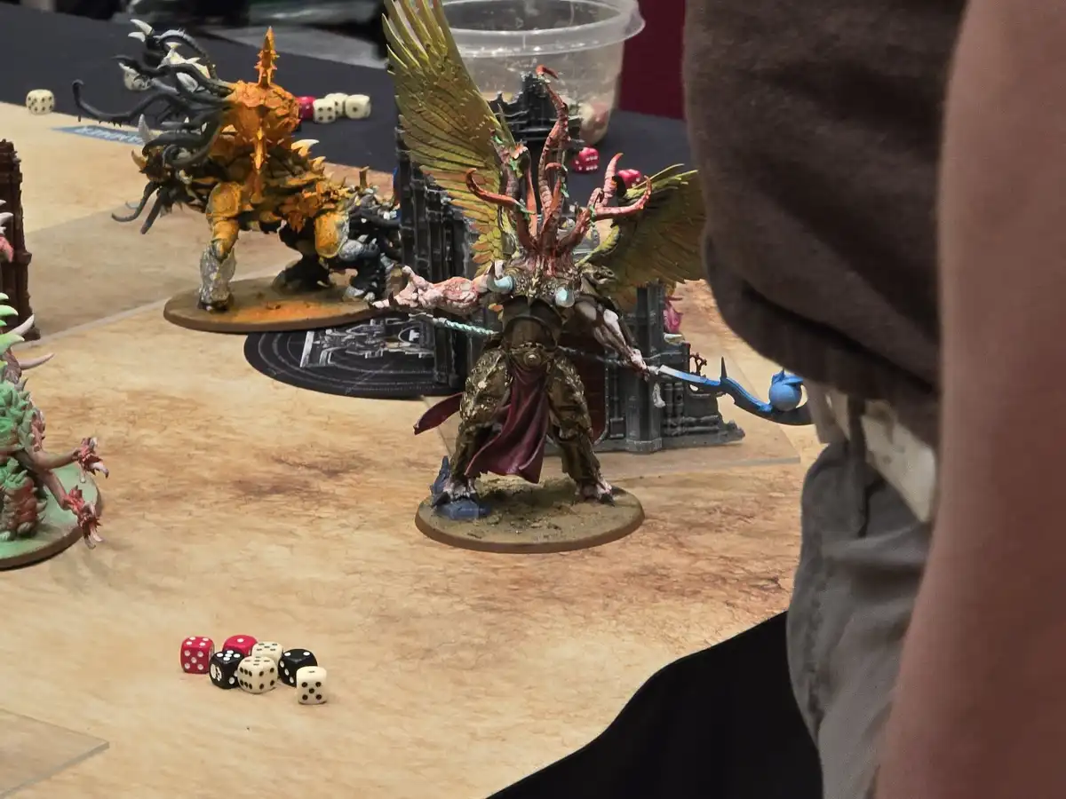 A photo of a tabletop miniature wargame in progress, showing several intricately painted fantasy miniatures on a gaming mat…