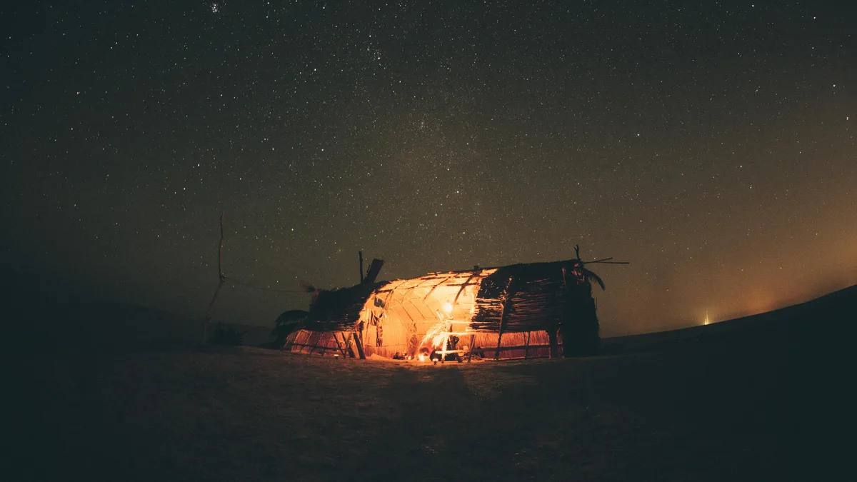 A canvas of indigo stretches above, studded with diamonds as the Milky Way weaves its path across the sky. A glowing tent, a…