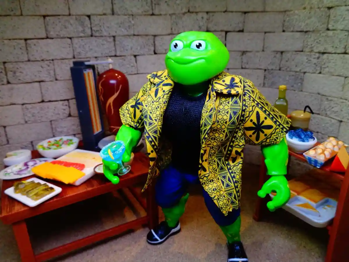 A green turtle action figure, dressed in a yellow patterned shirt and blue pants, stands in front of a miniature dining…