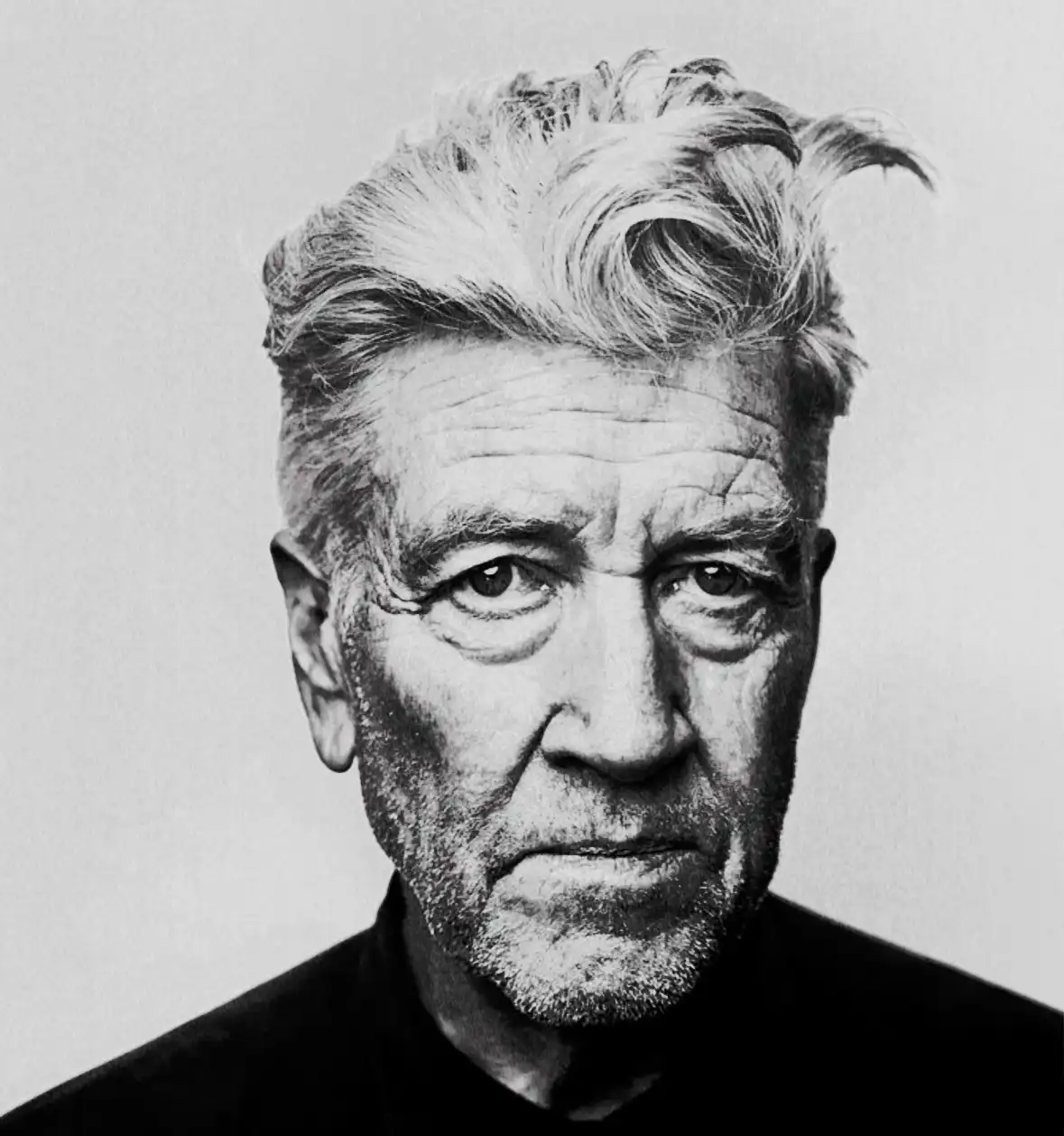 A black-and-white portrait of an older man with intense, weathered features, deep wrinkles, and wild gray hair, looking…