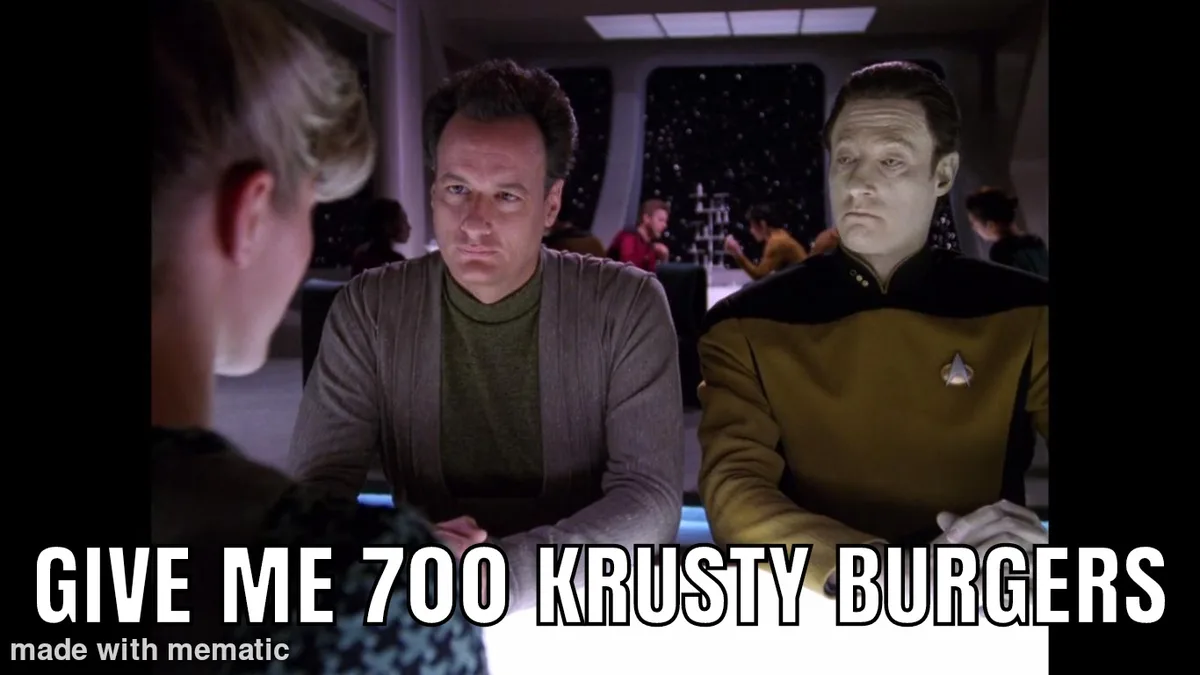 Two men in Star Trek uniforms sit at a table in a spaceship's mess hall, looking serious and slightly annoyed as they face a…