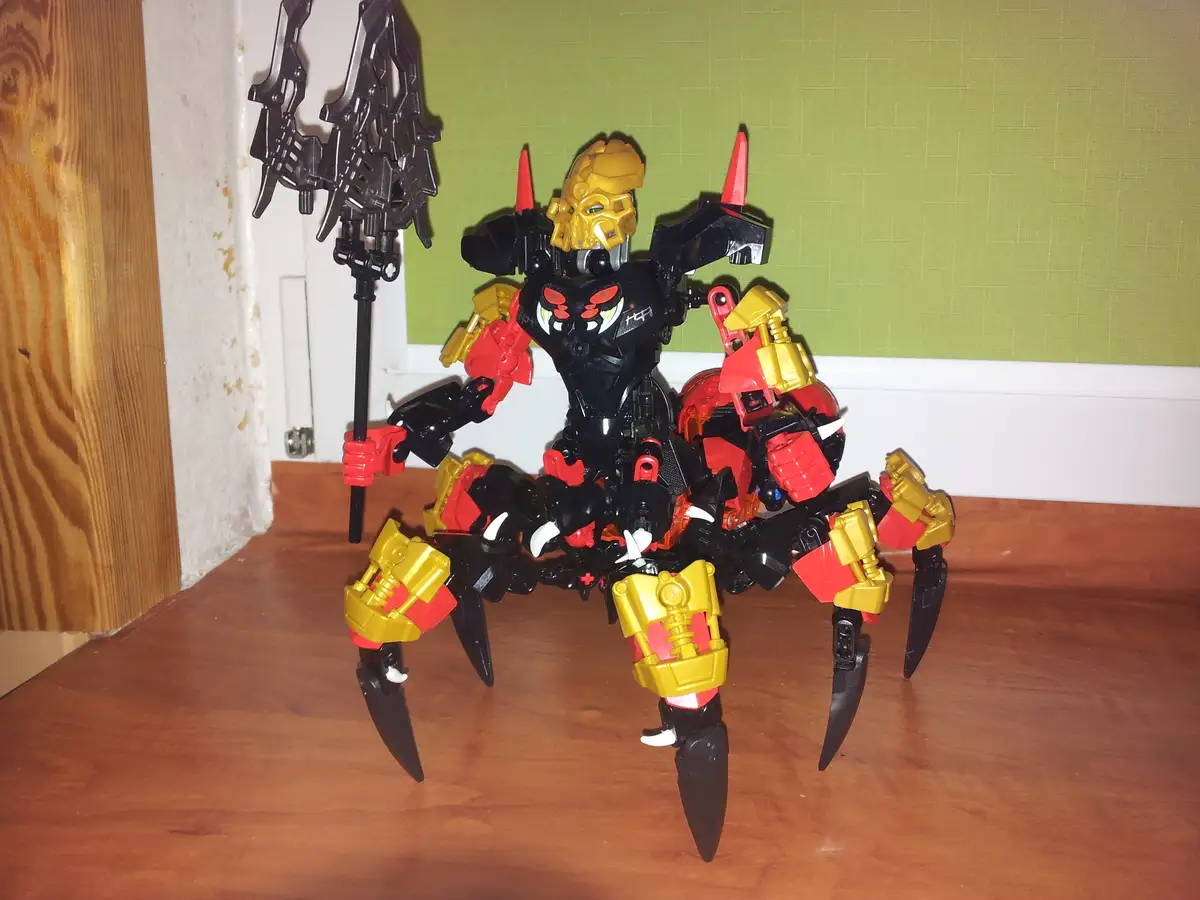 A custom-built Bionicle-style action figure with a black, red, and gold mechanical body, multiple spider-like legs ending in…