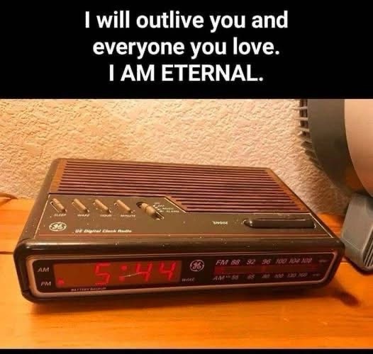 A vintage GE digital clock radio with a red LED display showing 5:44 AM sits on a wooden surface. The image has white text…