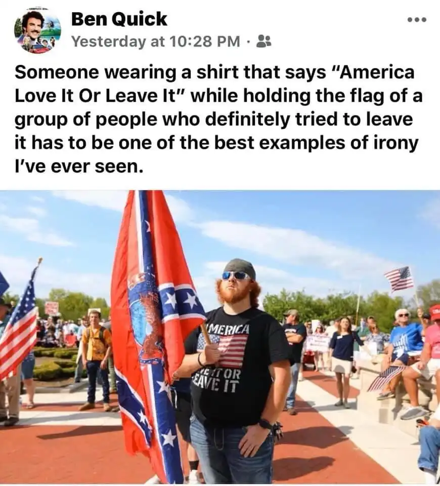 A man with a red beard and sunglasses wears a black t-shirt that reads 'AMERICA LOVE IT OR LEAVE IT' while holding a large…