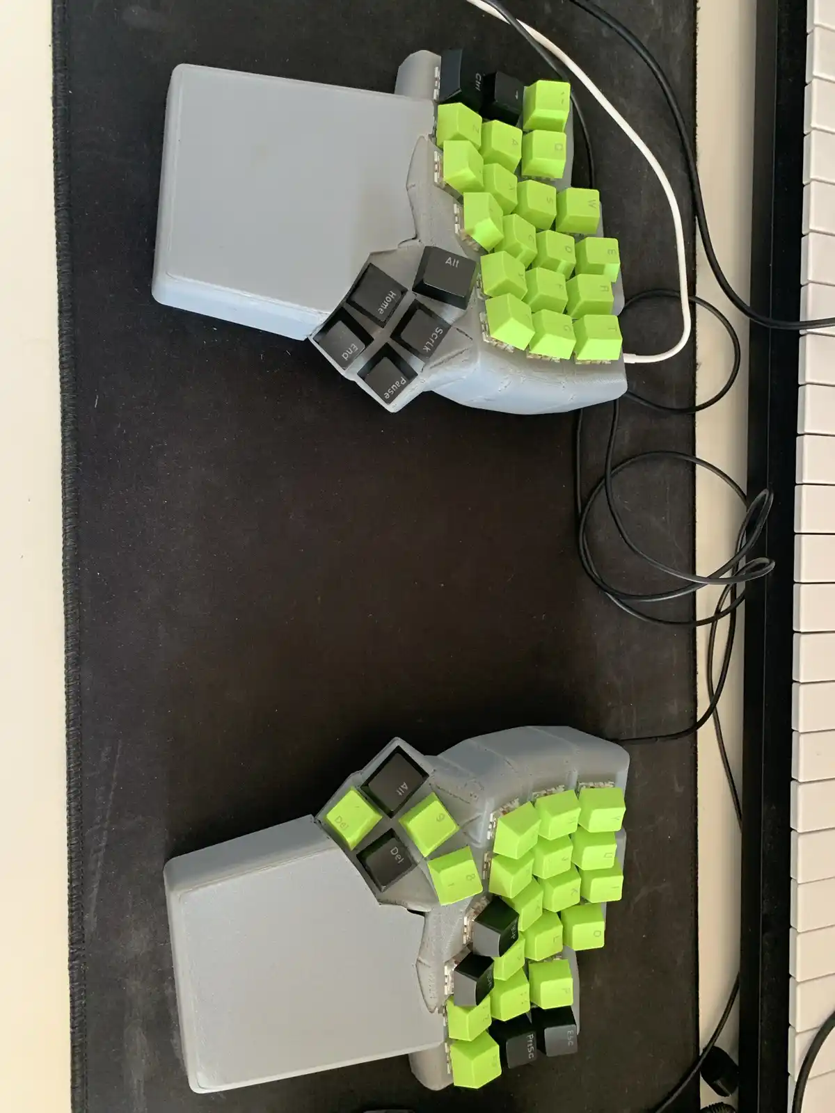 An overhead photo shows two custom-built ergonomic keyboards shaped like hands, each with bright green keycaps and black…