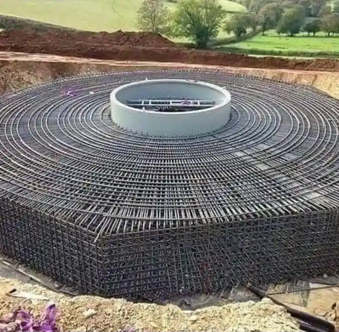 a large circular construction site with concentric layers of steel rebar forming a massive foundation, surrounding a central…