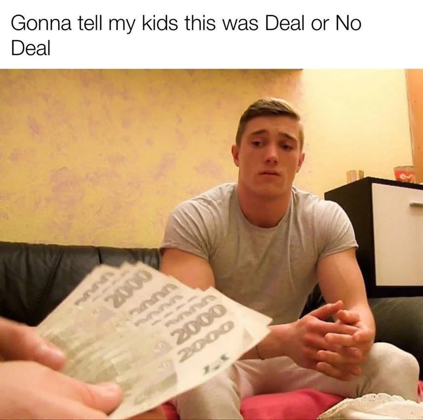 A young man sits on a couch looking shocked and overwhelmed as another person holds out several 2000 denomination banknotes…