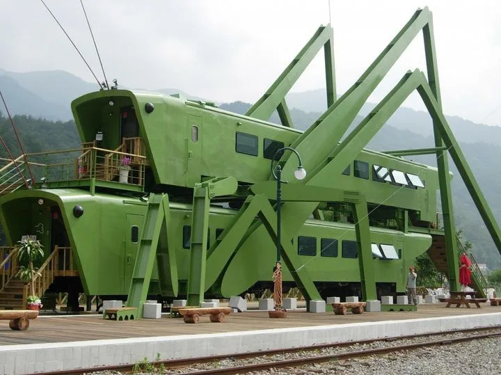 a large, bright green structure resembling a train carriage has been creatively modified to look like a giant cricket…
