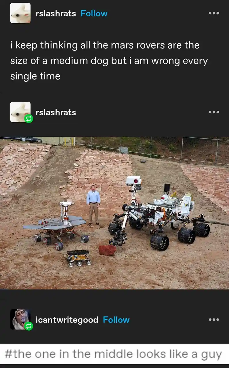 The image shows three Mars rovers displayed outdoors on reddish-brown dirt, with a man standing between them for scale. The…