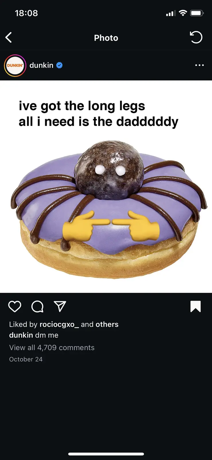 A purple-frosted donut with chocolate drizzle legs and a chocolate ball head with white eyes, overlaid with two pointing…