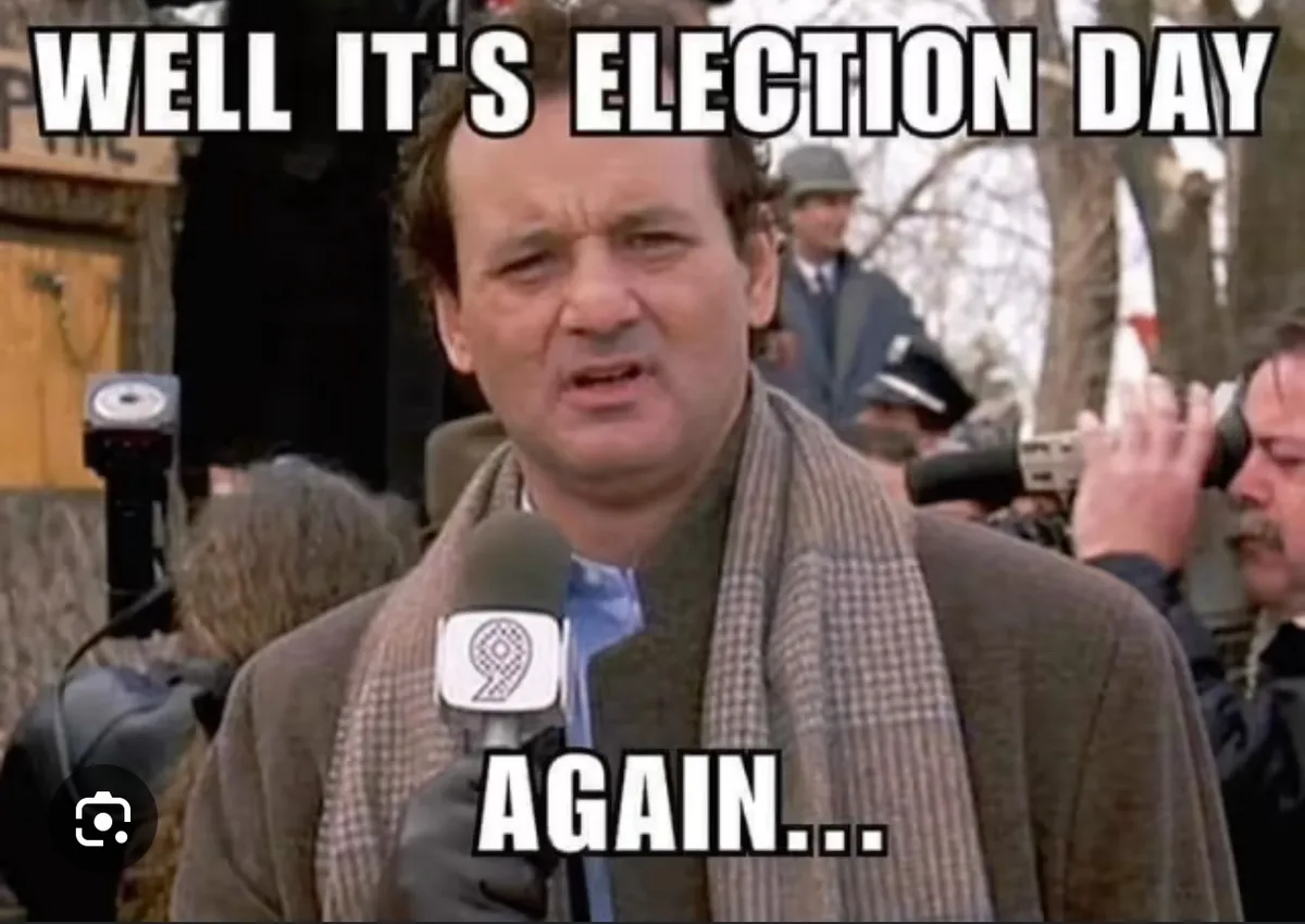 A man in a brown coat and scarf, holding a microphone with a '9' logo, looks exasperated while surrounded by reporters and…