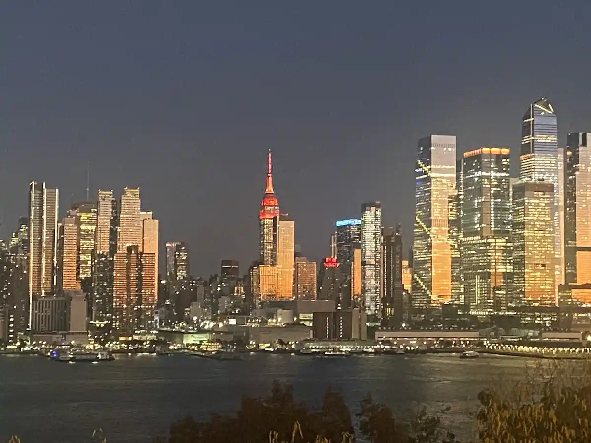 A nighttime photograph of the New York City skyline, featuring illuminated skyscrapers including the Empire State Building…