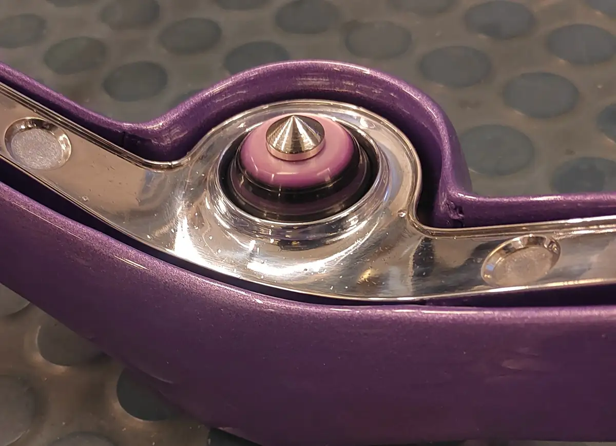 A close-up photo shows a purple and chrome mechanical device, possibly a piece of exercise equipment, with a prominent pink…