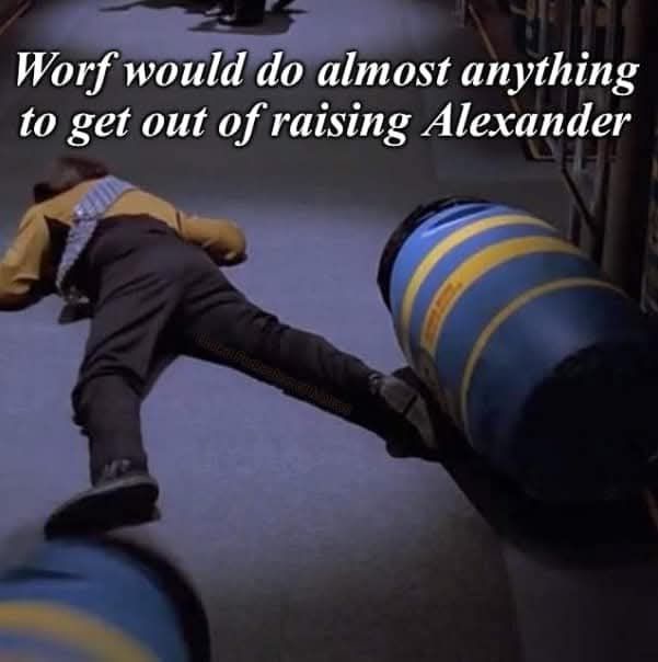 A person in a yellow Star Trek uniform is shown lying on their back on a floor, kicking a large blue and yellow striped…