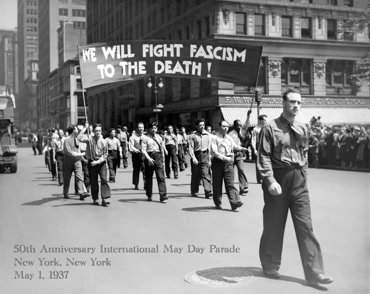 A black-and-white historical photo from May 1, 1937, shows a group of men marching in the 50th Anniversary International May…