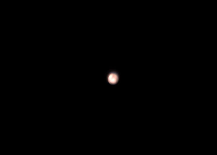 A blurry, low-resolution image shows a single, faintly glowing orb against a completely black background, resembling a…