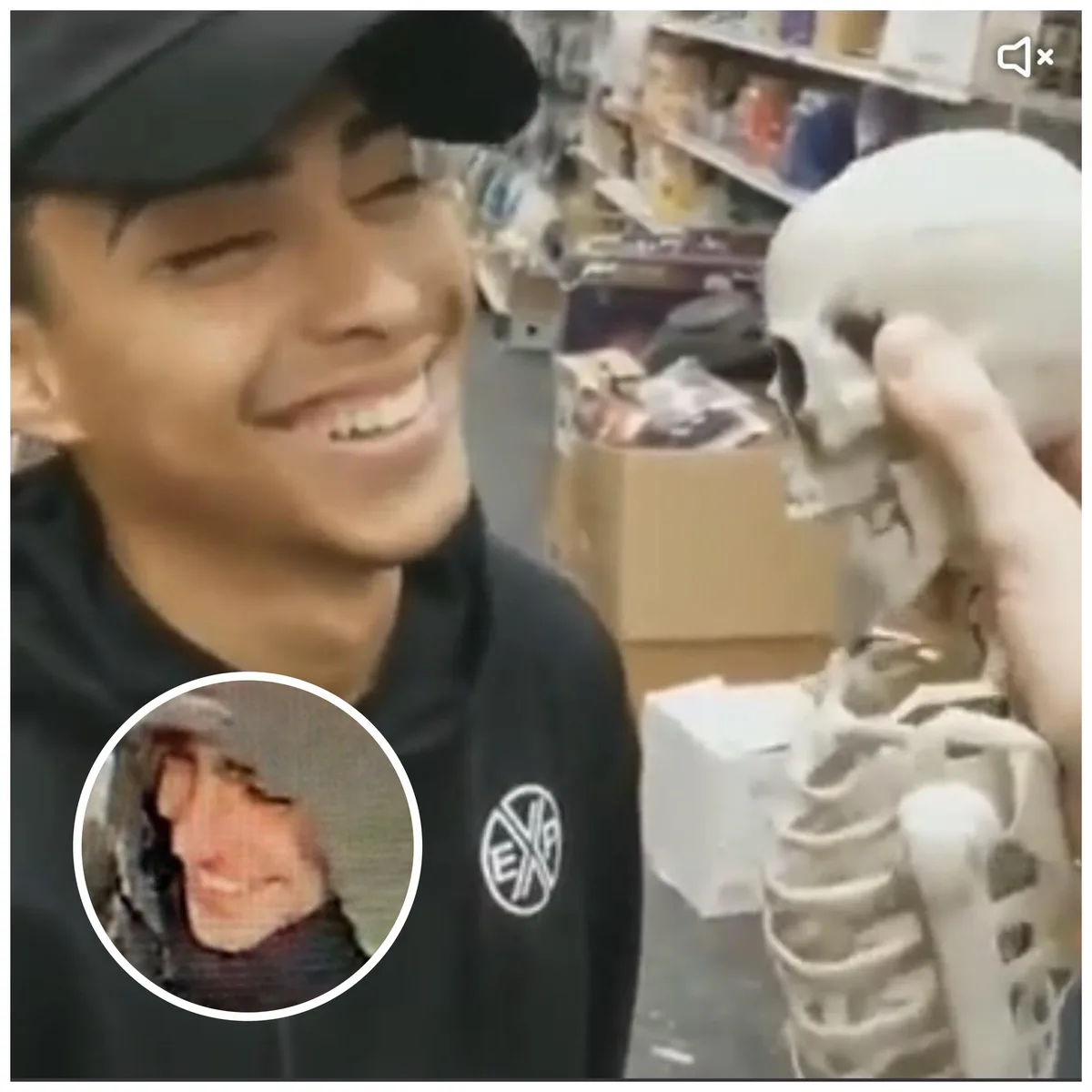 A young man in a black hoodie and cap laughs hysterically while looking at a skeleton prop being held up to his face. A…