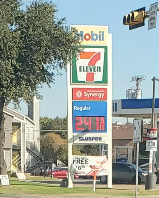 A Mobil gas station sign with a 7-Eleven logo on top, displaying 'Regular' gas at $2.419 per gallon. The sign also features…