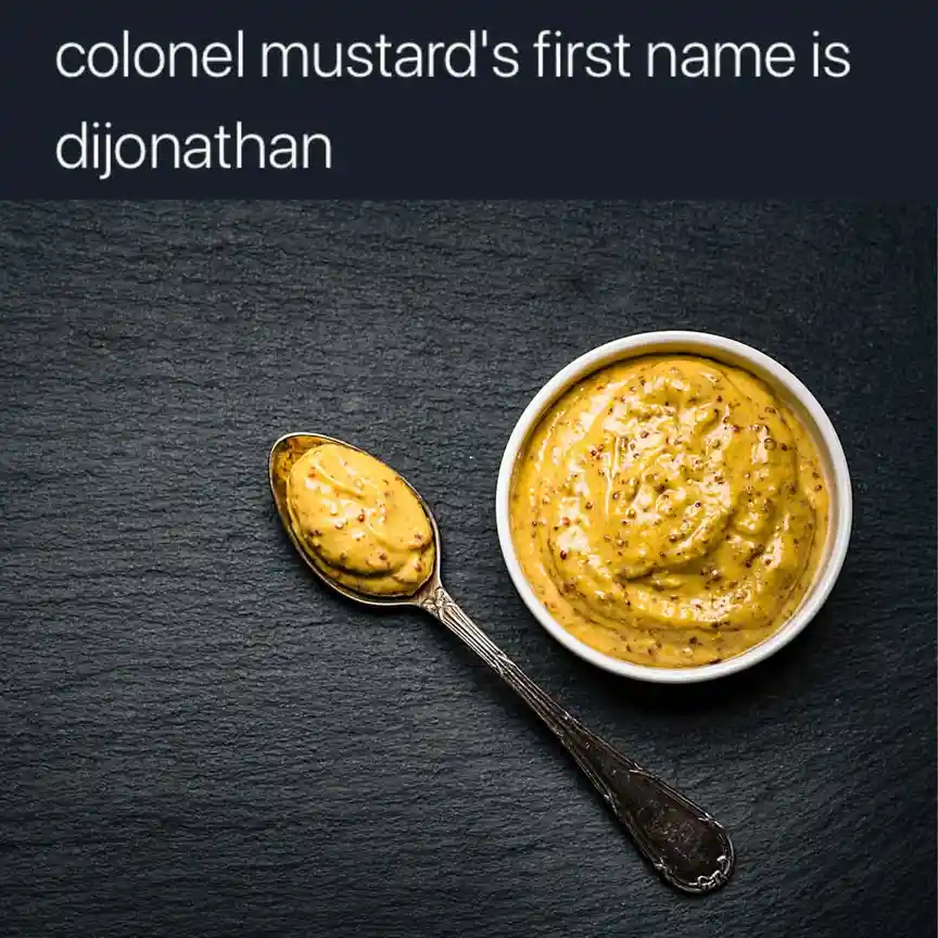 A white bowl and a silver spoon filled with yellow mustard sit on a dark slate surface. White text at the top reads 'colonel…
