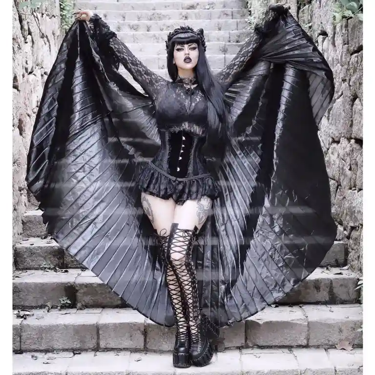 A woman in a full black gothic outfit with lace, a corset, and thigh-high boots stands on stone steps, dramatically holding…
