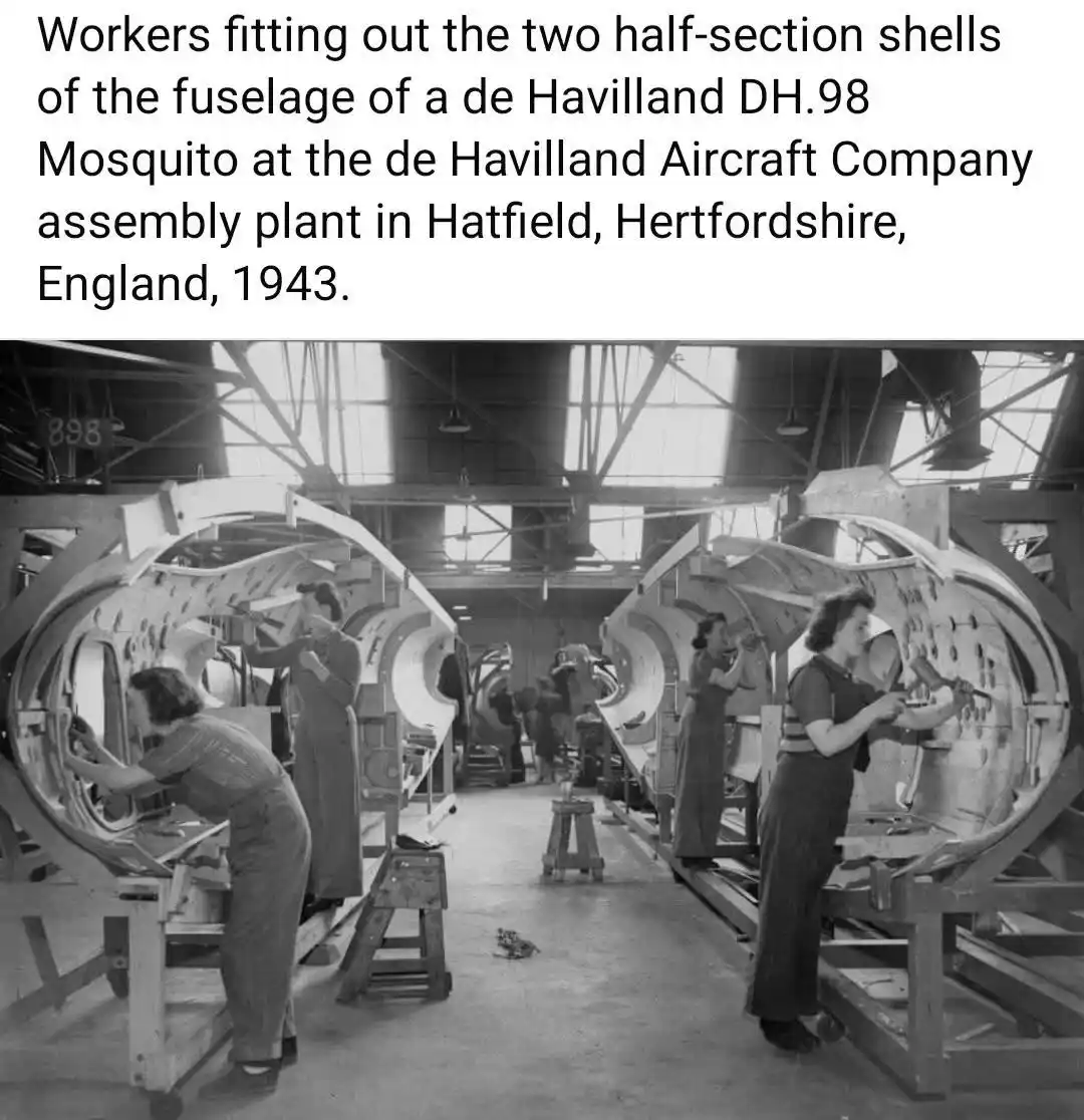 A black-and-white historical photograph shows several female workers in overalls assembling the fuselage halves of a de…