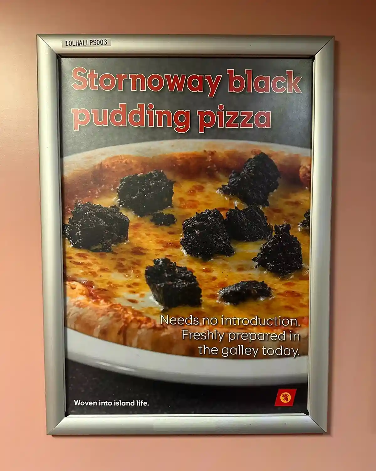 A framed advertisement poster for a 'Stornoway black pudding pizza' shows a pizza with melted cheese and chunks of black…