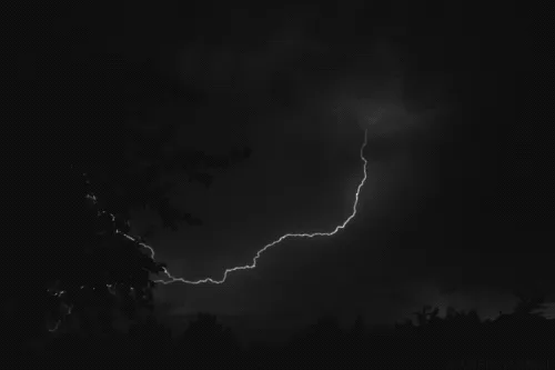 The image shows a dark night sky with tree silhouettes at the bottom. A jagged lightning bolt appears in the top left, then…