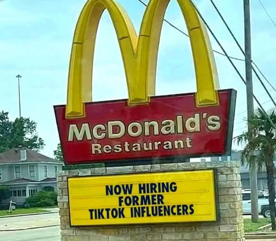 A McDonald's restaurant sign with its iconic golden arches and red background is shown, mounted on a stone pillar. Below it…