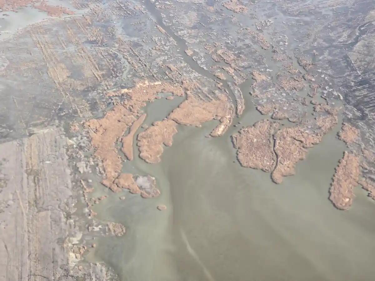 An aerial view of a muddy river with brown sediment patches and winding channels, overlaid with the text 'this is the river…