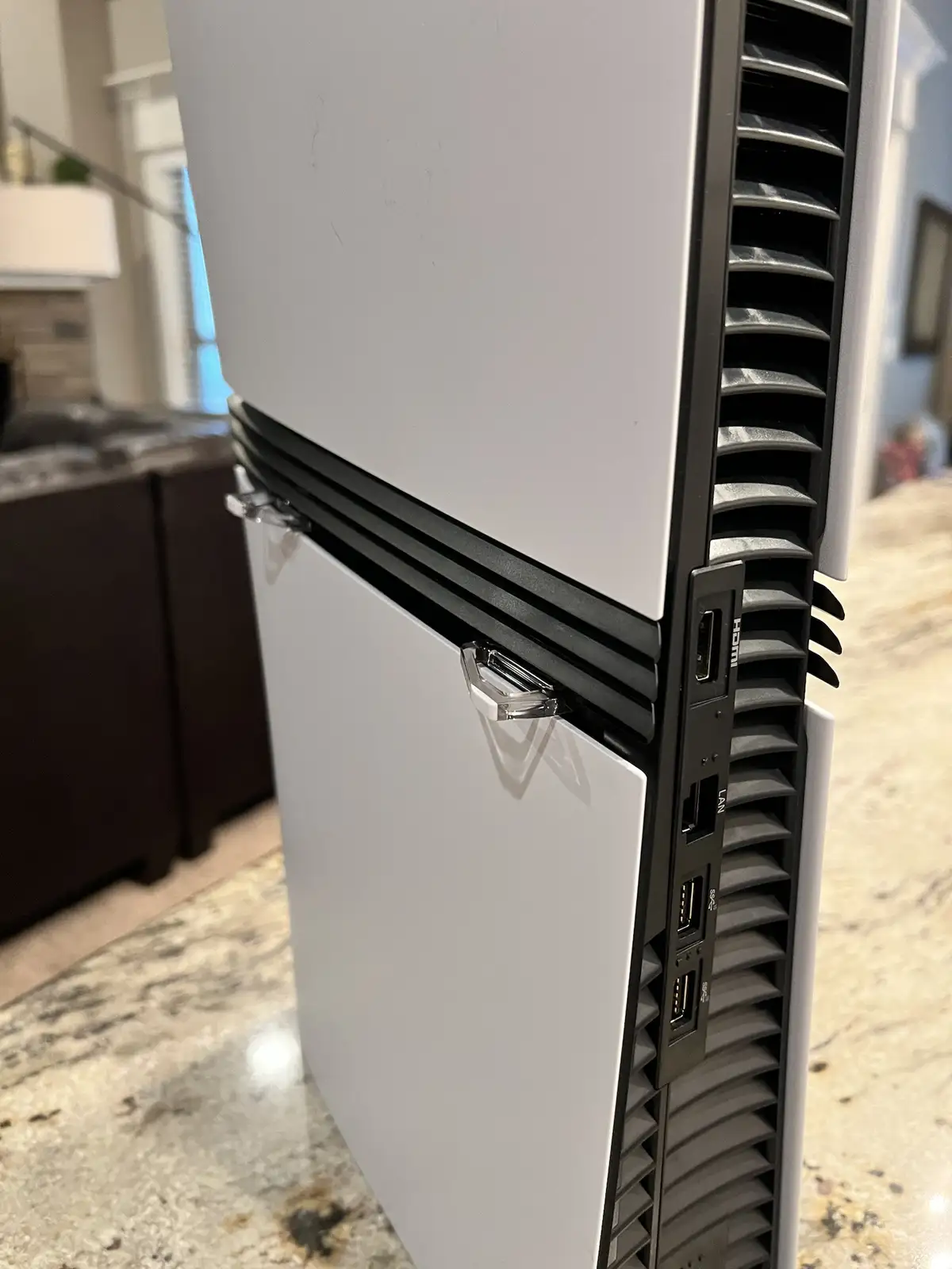 A close-up shot of a white refrigerator's side, showing its ventilation grille and ports, including HDMI, LAN, and USB…