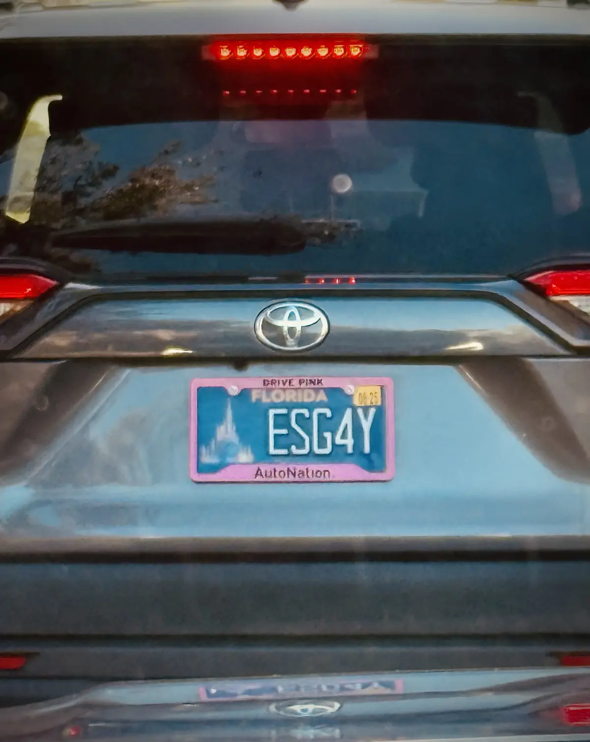 The rear of a dark-colored Toyota vehicle shows a Florida license plate with the registration number ESG4Y. The plate has a…
