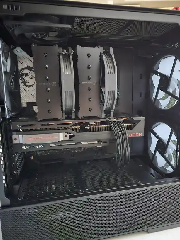 The image shows the interior of a black computer case with two large, identical CPU coolers mounted on the motherboard…