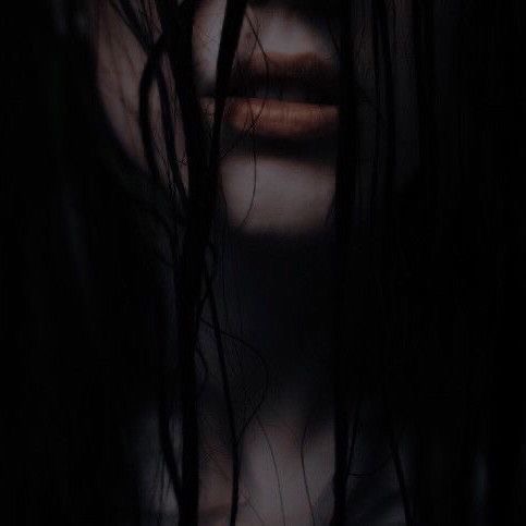 A dark, moody close-up of a person's lower face, with long, wet-looking black hair partially obscuring their features. Only…