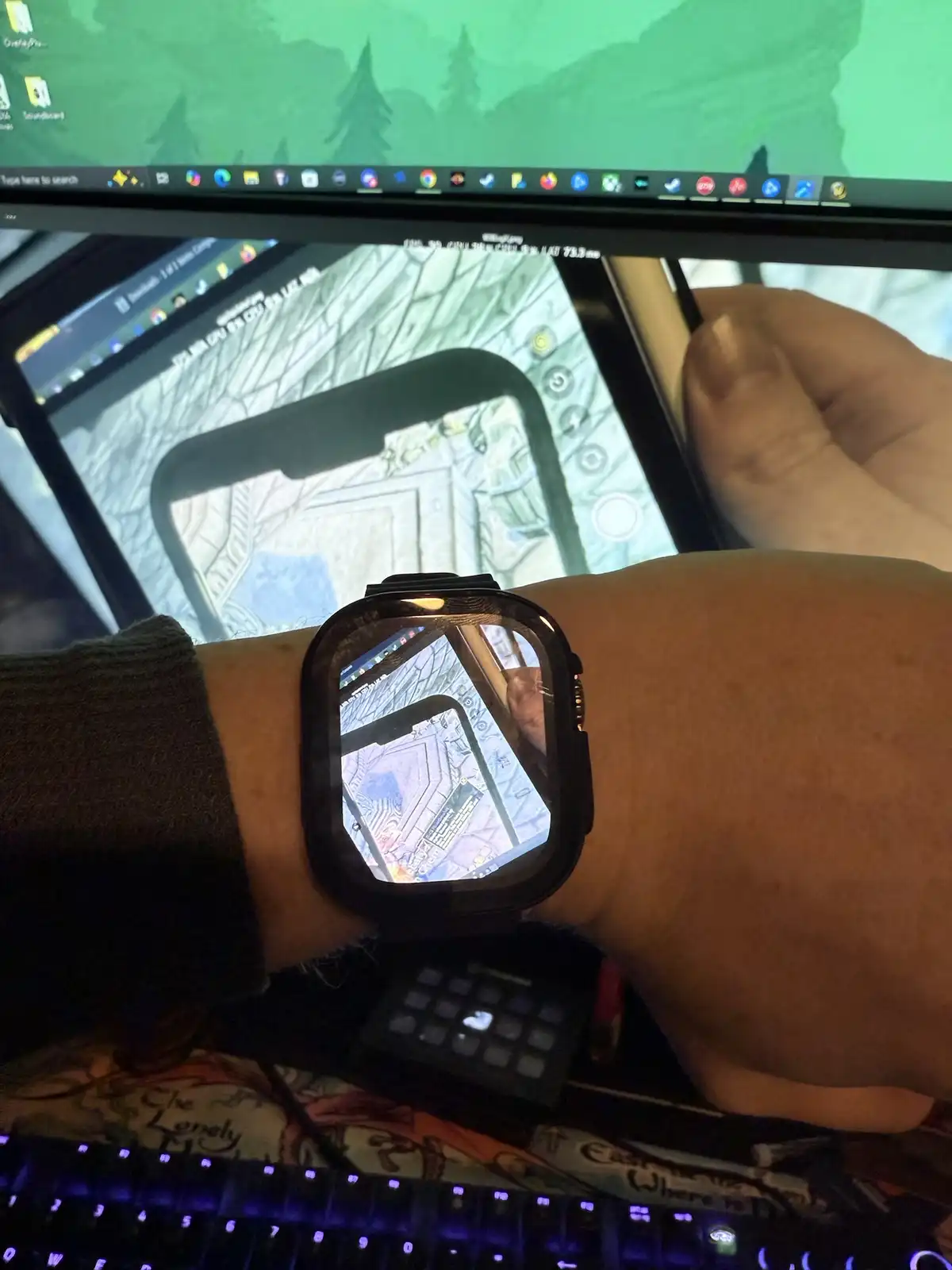 A person's wrist wearing a smartwatch displays a mirrored reflection of a mobile game being played on a tablet, which is…