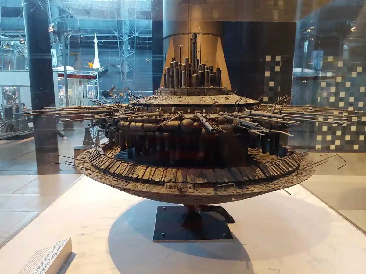 A detailed, intricate model of a spaceship, likely from a science fiction film, is displayed in a museum glass case. The…
