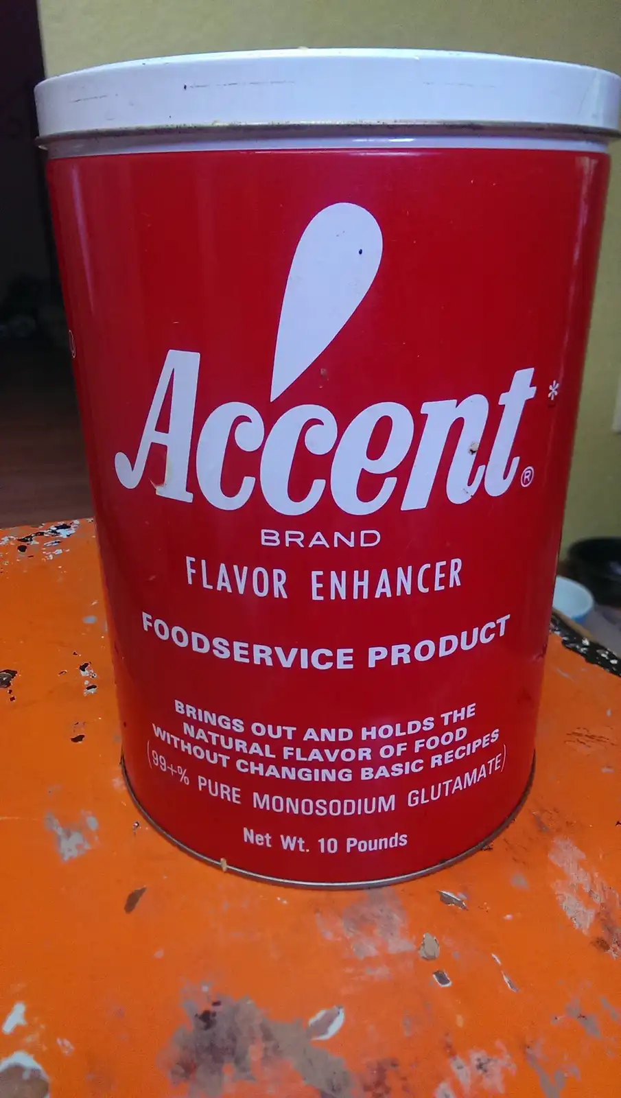 A large red canister of Accent brand flavor enhancer, labeled as a foodservice product containing 99+% pure monosodium…