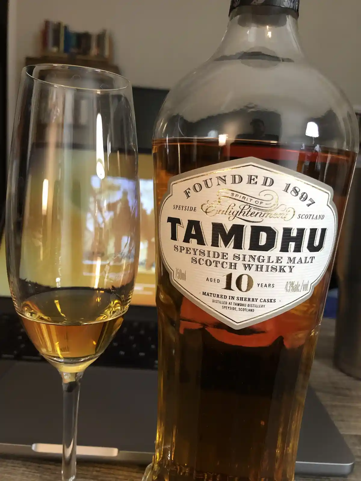 A bottle of Tamdhu 10-year-old Speyside single malt scotch whisky sits next to a champagne flute containing a small amount…
