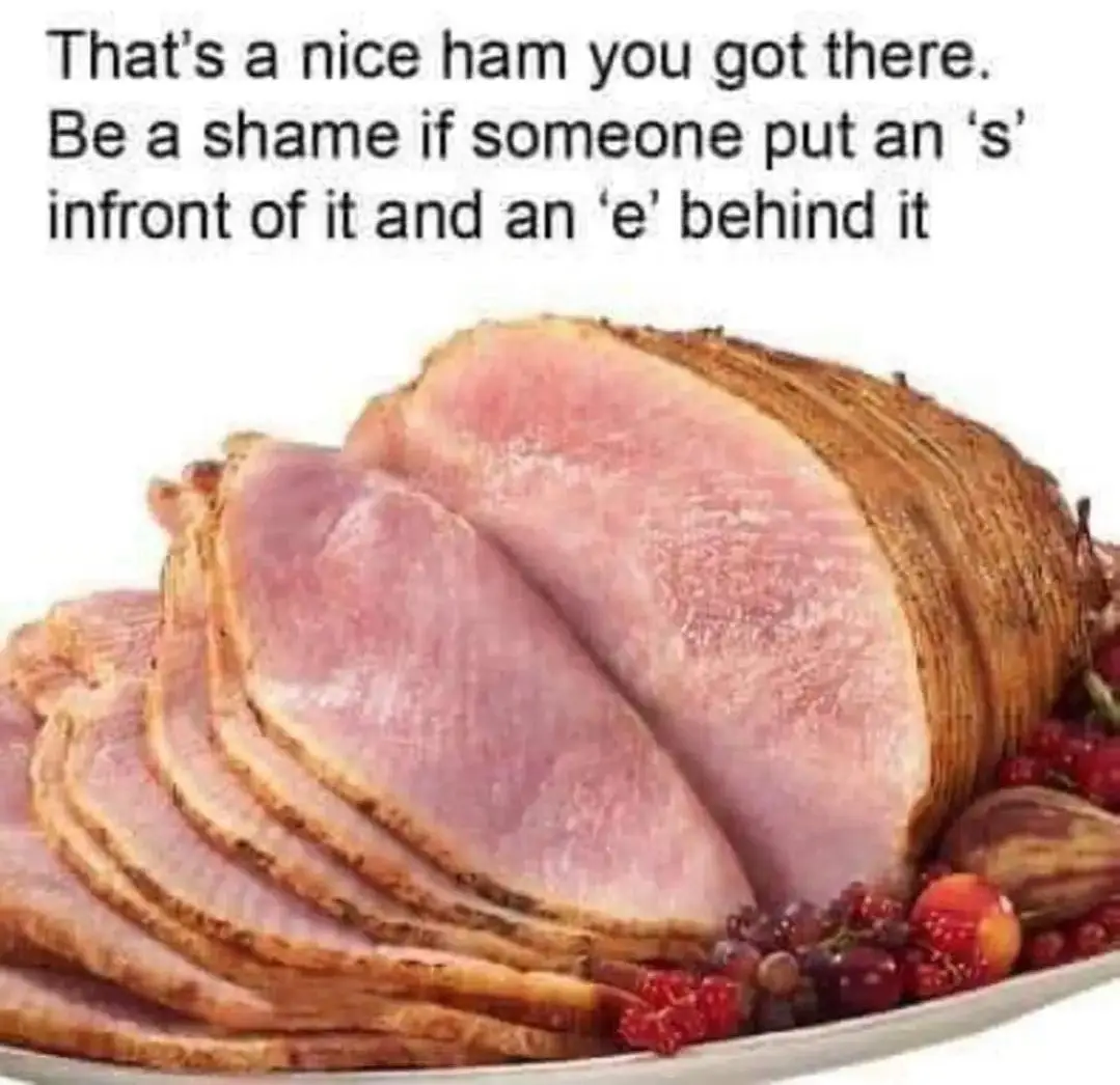 A close-up image of a roasted ham with several slices cut and fanned out on a platter, garnished with red berries and…