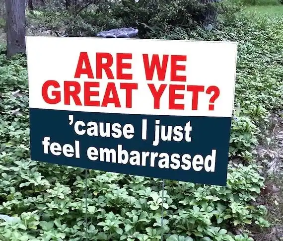 A yard sign with red text on a white background asks 'ARE WE GREAT YET?' and a dark blue section below says 'cause I just…