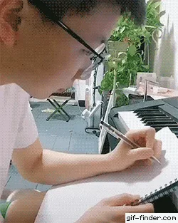 A sequence of six images shows a person in glasses writing in a notebook. A small, fluffy white and light brown cat slowly…